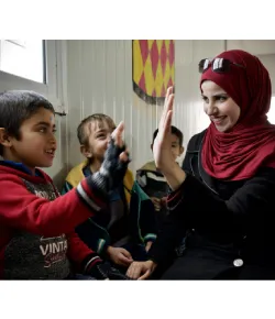 A female teacher doing a high five to one young boy