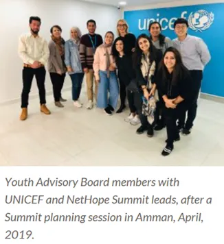 A group of women and men are standing in front of a UNICEF rollup.