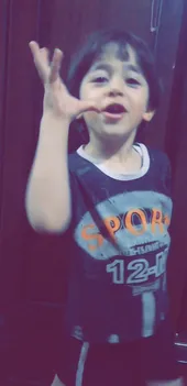 A young boy is singing and raising his left hand