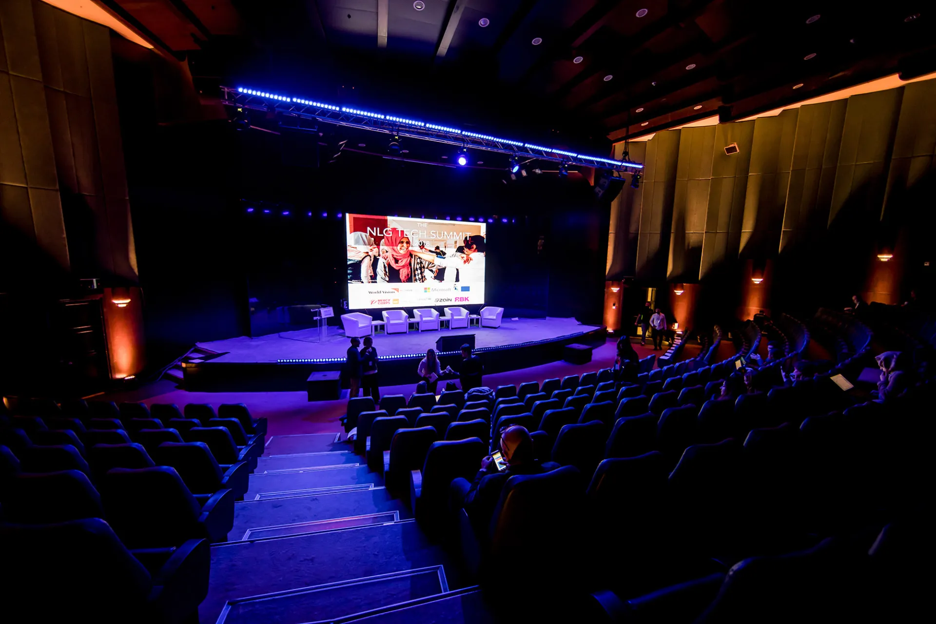 A crowd in an amphitheater shown from the back with purple light