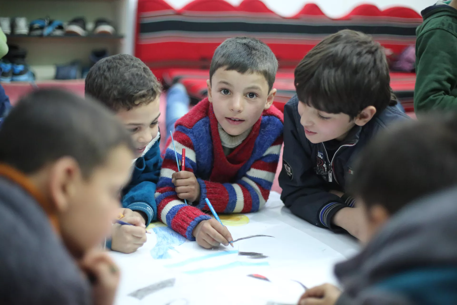 Young boys attend a basement school in besieged East Ghouta and are drawing on a table