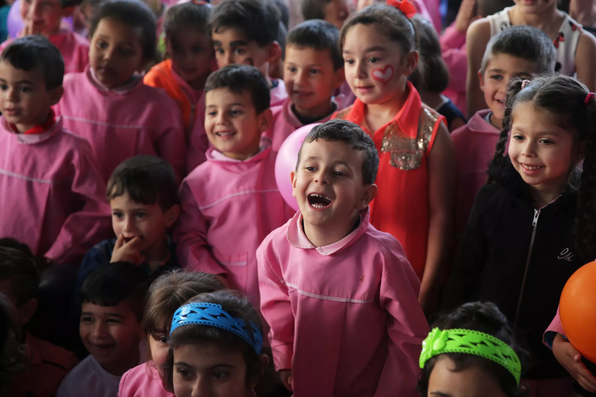 A group of young girls and boys dressed in pink and smiling