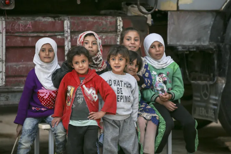 A group of 7 young girls is sitten on a table behind a truck