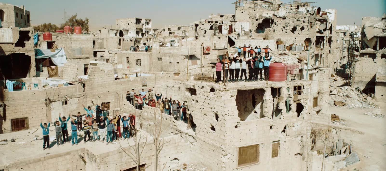 Several groups of children are waiving from rooftops