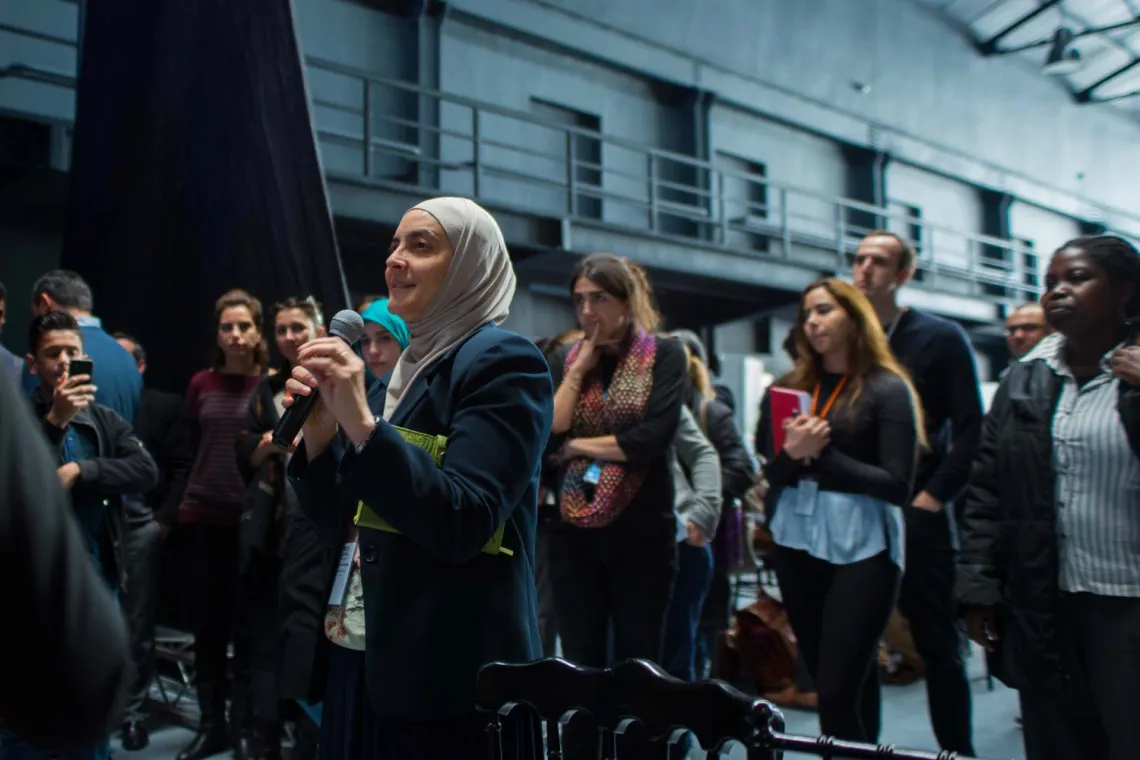A woman speaking in a micro, surrounded by a crowd of young women