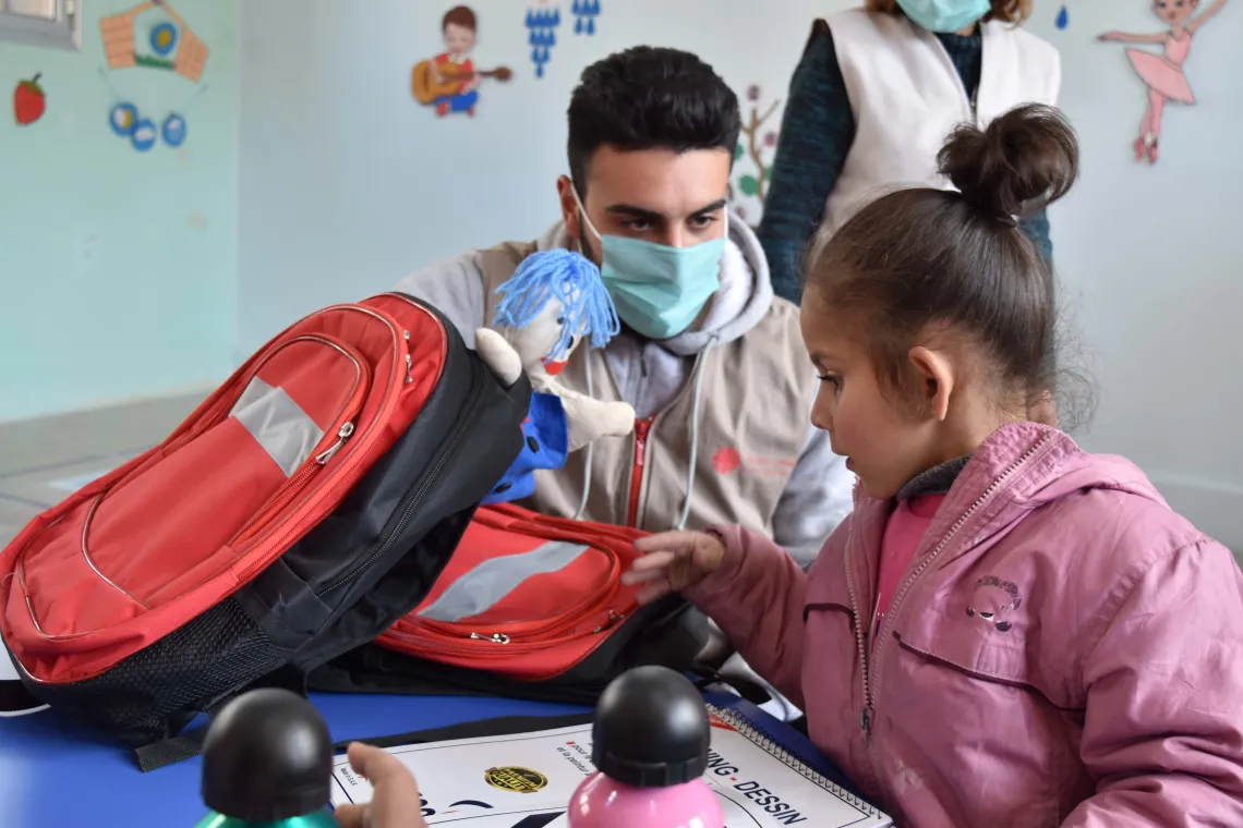 A man is helping a young girl to study and is giving her a schoolbag