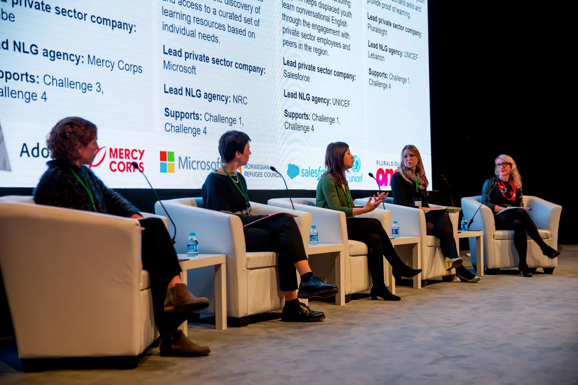 Four women sitting on a stage debating