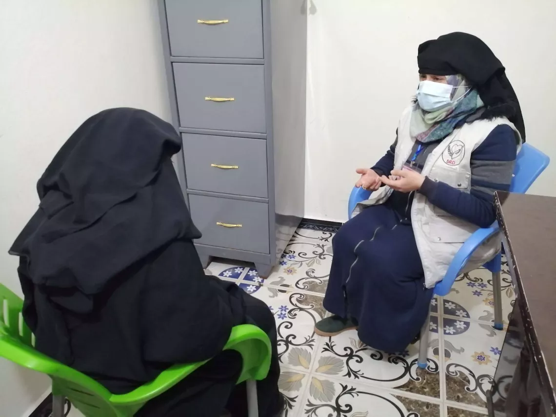 A female doctor is listening to her patient, they are both sitting on chairs
