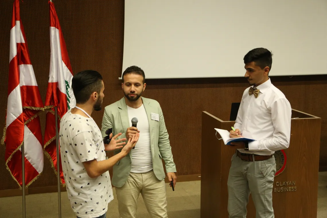 Three young men speaking at a stage