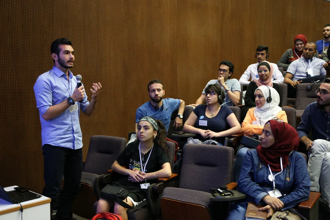 A young man standing in front of a crowd and speaking in a micro