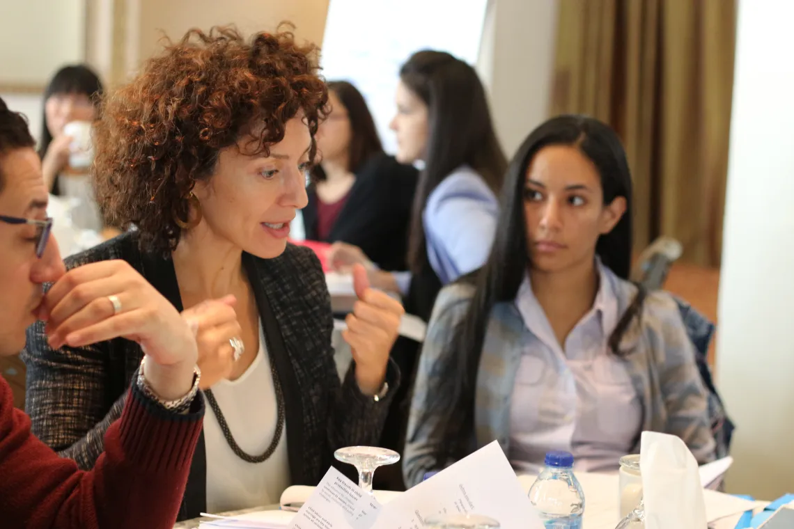 A woman sitting at a table and speaking to two woman