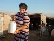 A woman smiling and carrying a jar of water outside