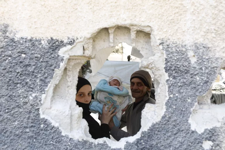 Through a hole in a wall, we can see two parents carrying a one-month-old baby girl.